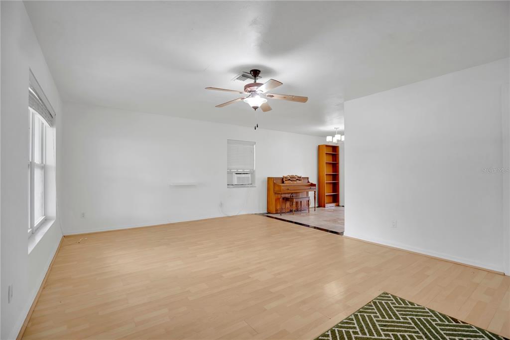 A living room features gray furniture, a ceiling fan, a wall-mounted television, and carpeted floors — 682 MERRIMAC STREET, DELTONA, FL