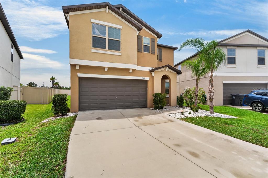 A two-story tan stucco house with a two-car garage and a concrete driveway — 5119 WHITE CHICORY DRIVE, APOLLO BEACH, FL