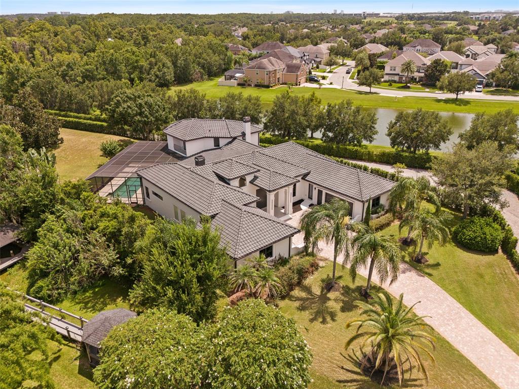 An aerial view shows a large house with a tiled roof, pool enclosure, and landscaped yard — 10352 BURRIS COURT, ORLANDO, FL