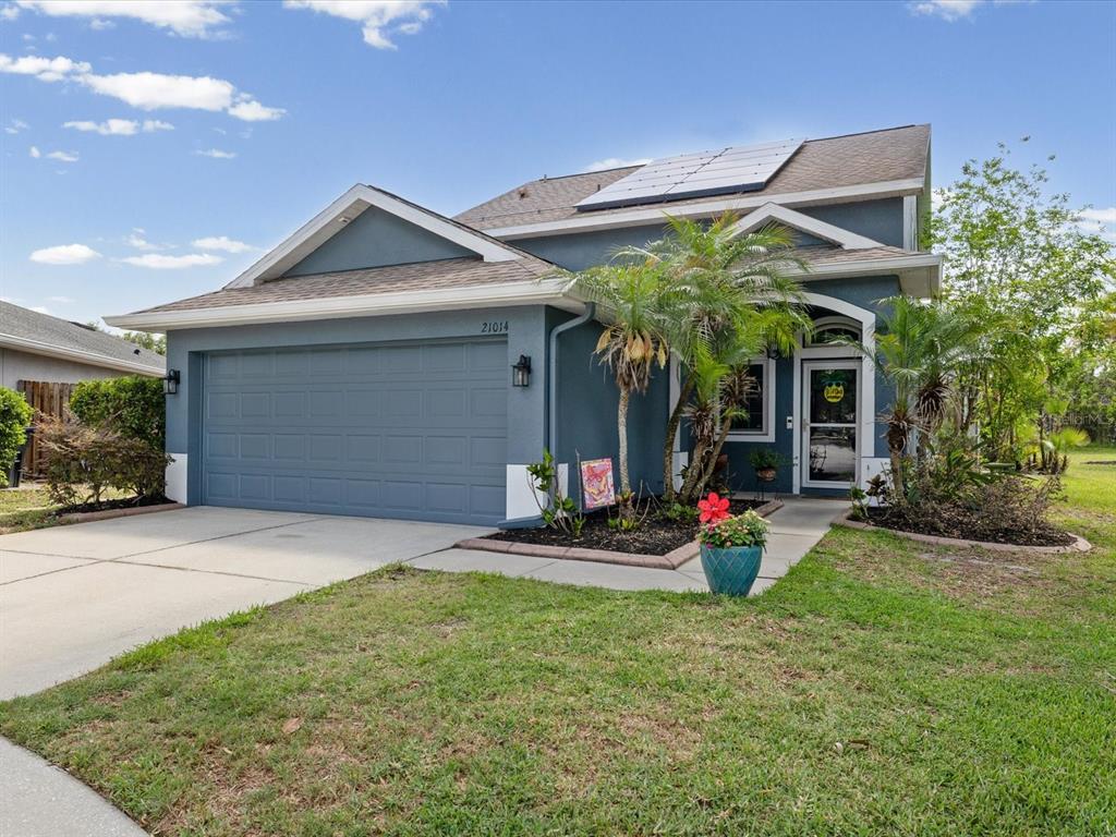 A blue single-story house with a two-car garage, solar panels, and a landscaped front yard — 21014 FOLLENSBY COURT, LAND O LAKES, FL