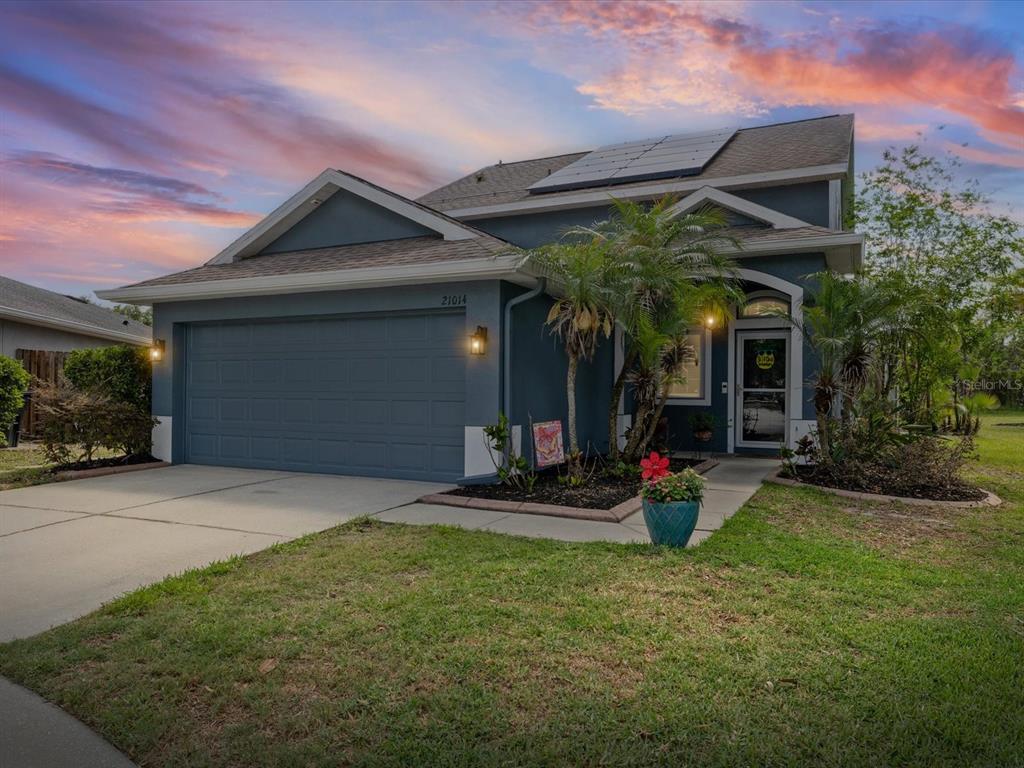 A blue single-story house with a two-car garage, solar panels, and a landscaped front yard — 21014 FOLLENSBY COURT, LAND O LAKES, FL