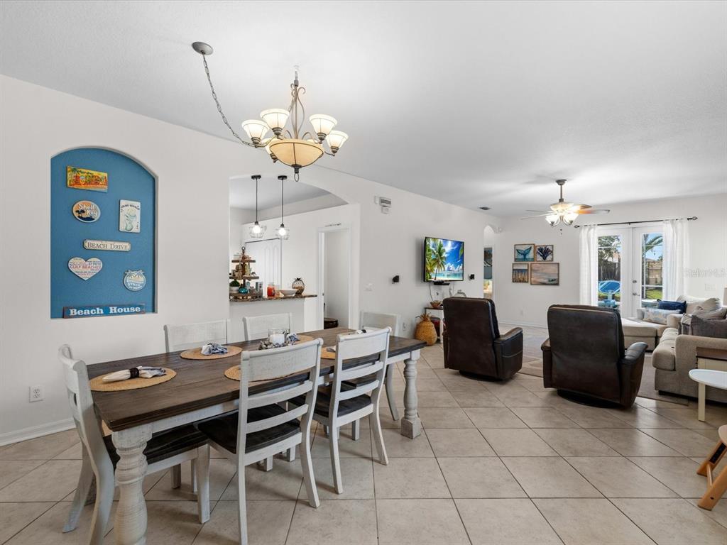 A dining area with a wooden table and white chairs opens into a living room — 21014 FOLLENSBY COURT, LAND O LAKES, FL