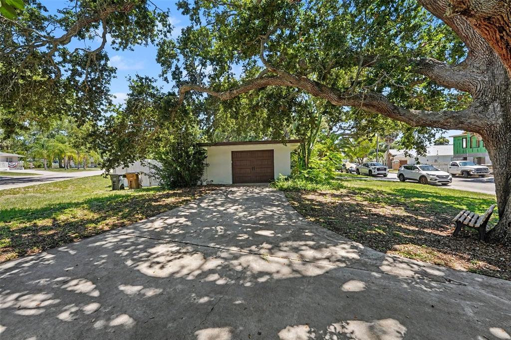 A detached garage with a brown door sits at the end of a concrete driveway — 217 GARDEN CIRCLE, BELLEAIR, FL