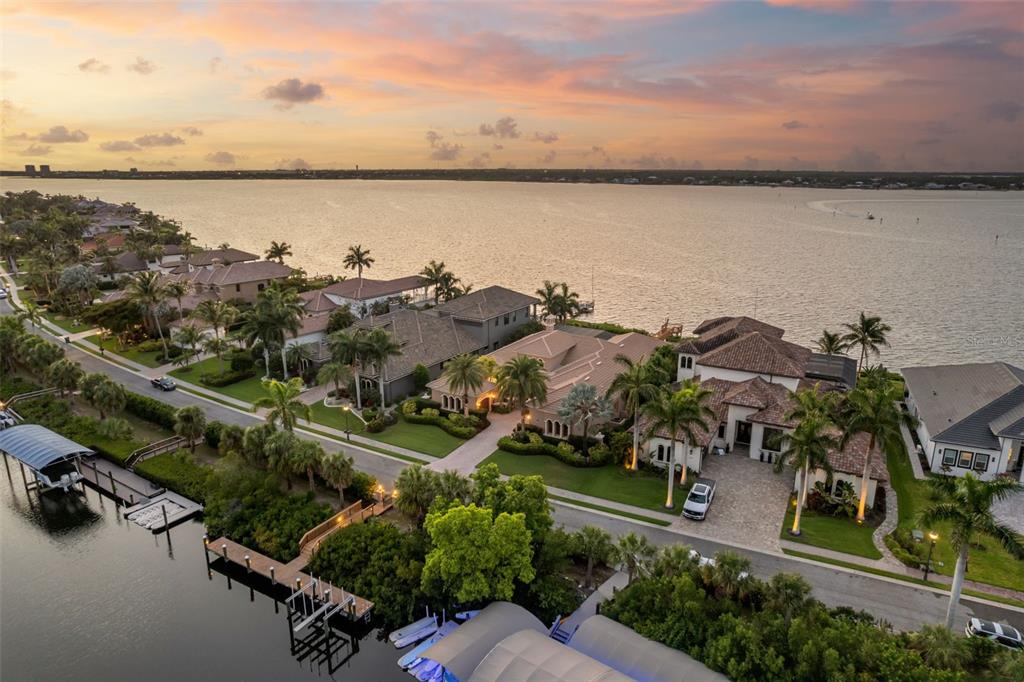 An aerial view shows waterfront luxury homes with docks along a canal at sunset — 4015 HAWK ISLAND DRIVE, BRADENTON, FL
