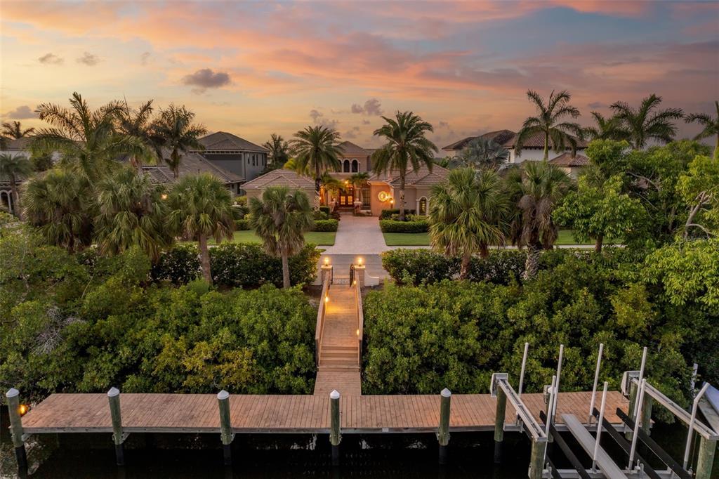 An aerial view of a waterfront home with a wooden dock and a paved walkway — 4015 HAWK ISLAND DRIVE, BRADENTON, FL