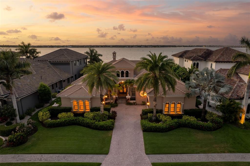 An aerial view of a waterfront house with a paved driveway and palm trees — 4015 HAWK ISLAND DRIVE, BRADENTON, FL
