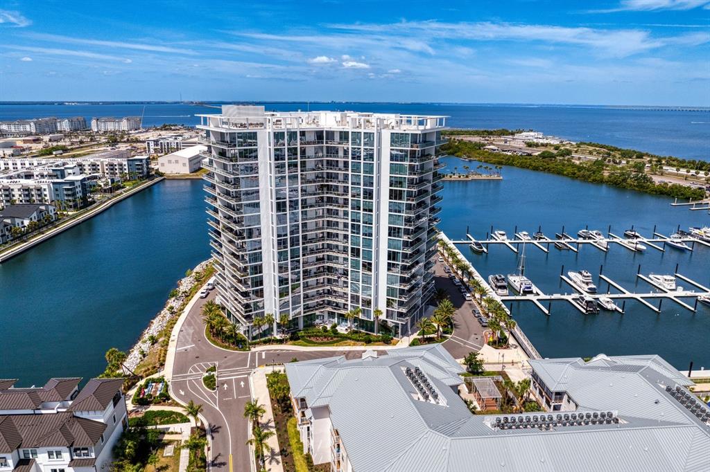 An aerial view shows a tall, modern residential building situated on a waterfront marina — 5120 MARINA WAY UNIT 10006, TAMPA, FL
