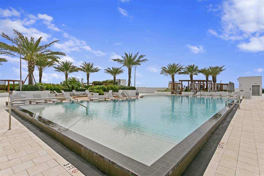 An outdoor swimming pool with a shallow entry and lounge chairs on a paved deck — 5120 MARINA WAY UNIT 10006, TAMPA, FL