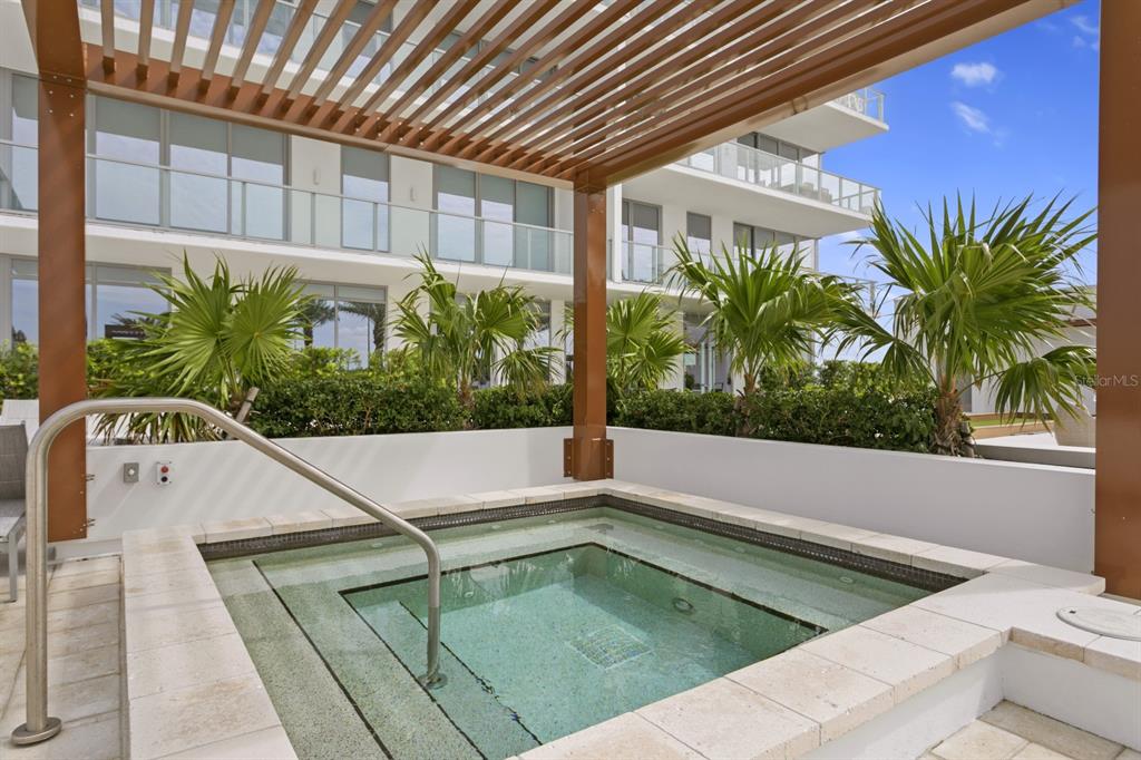 A square hot tub sits under a wooden pergola on a modern outdoor patio — 5120 MARINA WAY UNIT 10006, TAMPA, FL