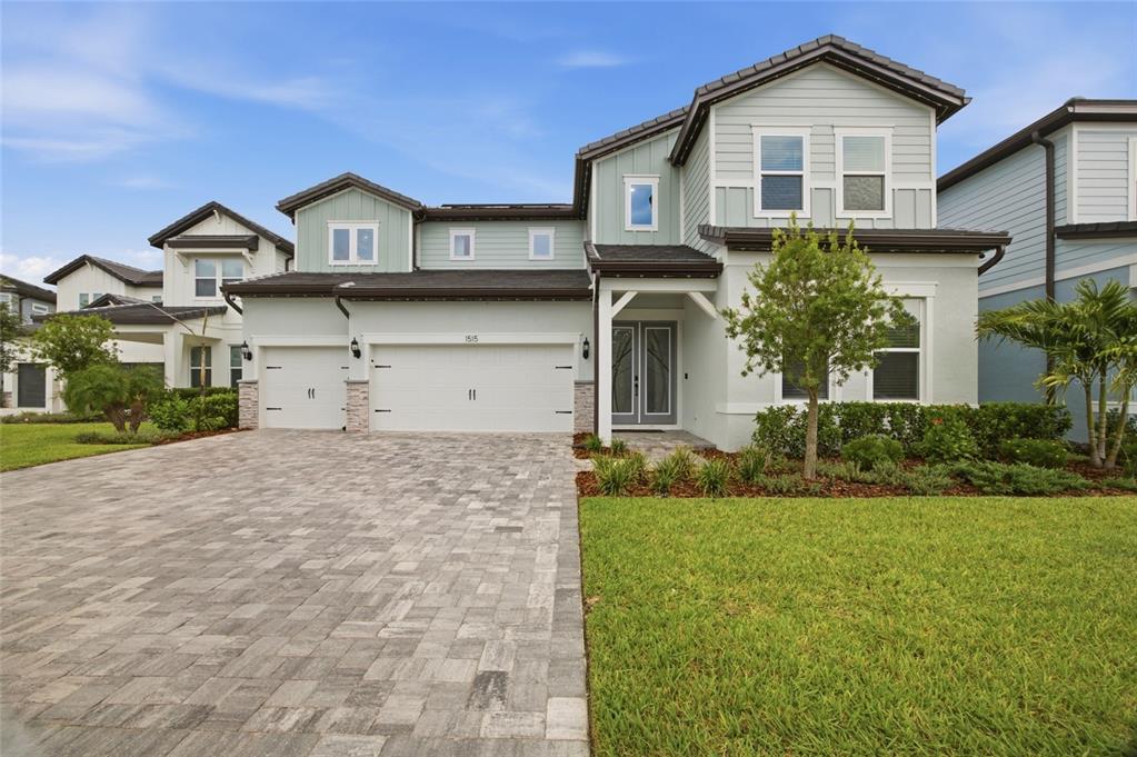 A two-story house with light green siding, a three-car garage, and a paved driveway — 1515 VALIER POINT, ZEPHYRHILLS, FL