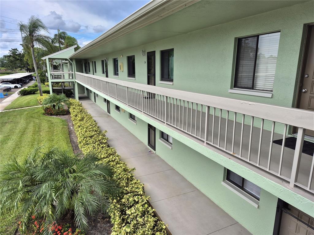An exterior view of a multi-story apartment building with a long balcony and green siding — 222 CARYL WAY, OLDSMAR, FL