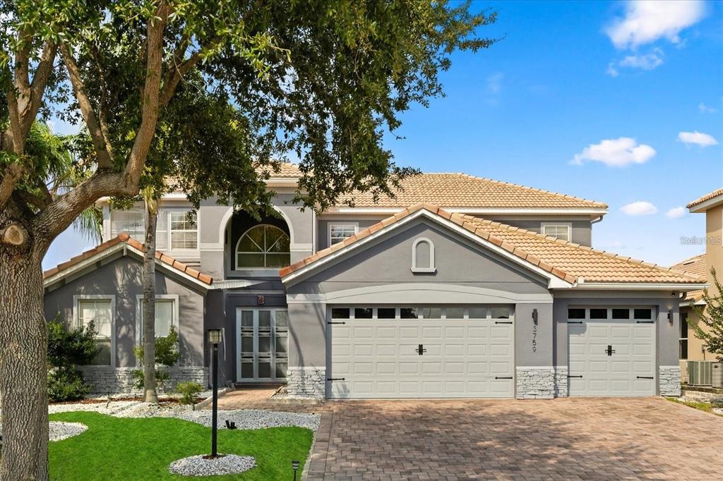 A two-story house with a gray exterior, a tiled roof, and a three-car garage — 3759 EAGLE ISLE CIRCLE, KISSIMMEE, FL