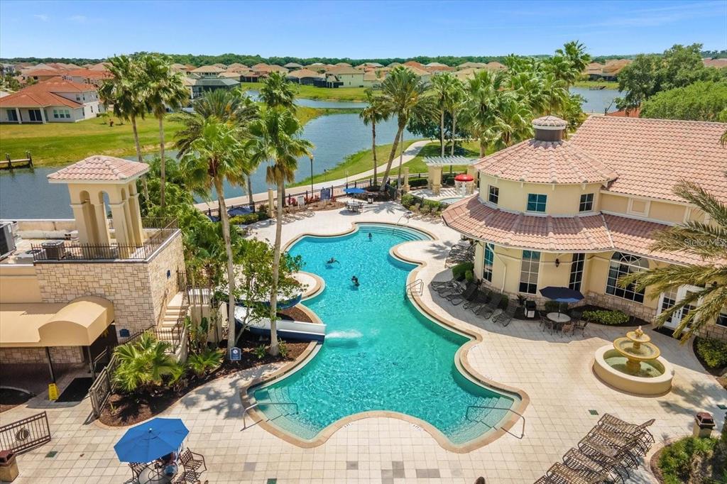 An aerial view of a community swimming pool with a waterslide, fountain, and clubhouse — 3759 EAGLE ISLE CIRCLE, KISSIMMEE, FL