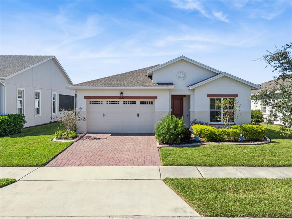 A single-story house with a brick driveway, two-car garage, and landscaped front yard — 2632 MEADOWEDGE LOOP, ST CLOUD, FL