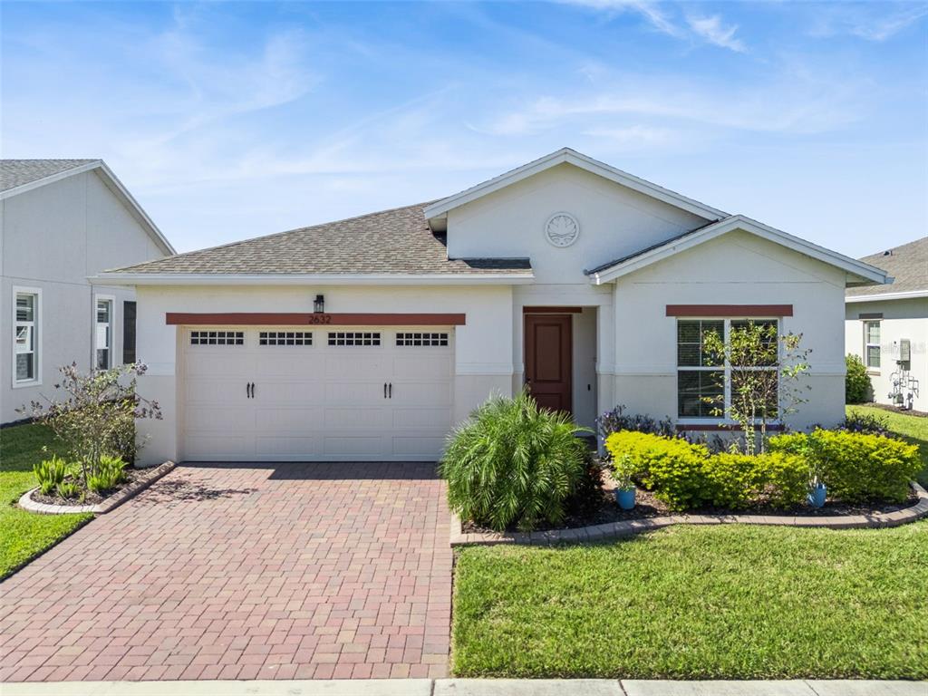 A single-story house with a beige stucco exterior, a brick driveway, and a two-car garage — 2632 MEADOWEDGE LOOP, ST CLOUD, FL