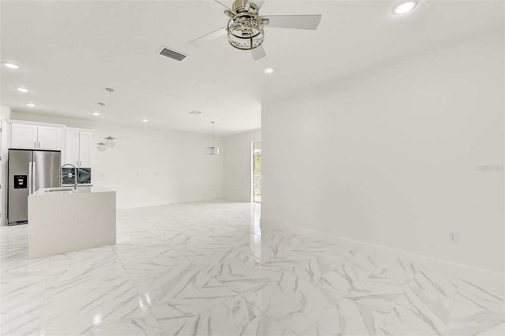 A bright, open-concept kitchen and living area featuring white marble-style tile flooring — 3889 WALKER ROAD, APOPKA, FL