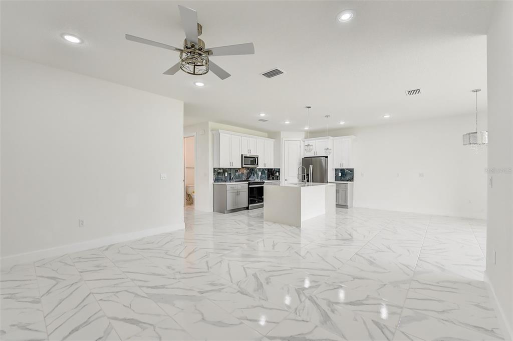 A bright, open-concept kitchen and living area featuring white marble-look tile flooring — 3889 WALKER ROAD, APOPKA, FL