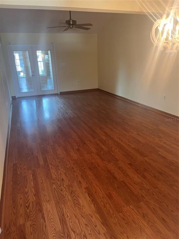 An empty room features wood-look flooring, a ceiling fan, and glass French doors — 15 COVE LANE, EUSTIS, FL