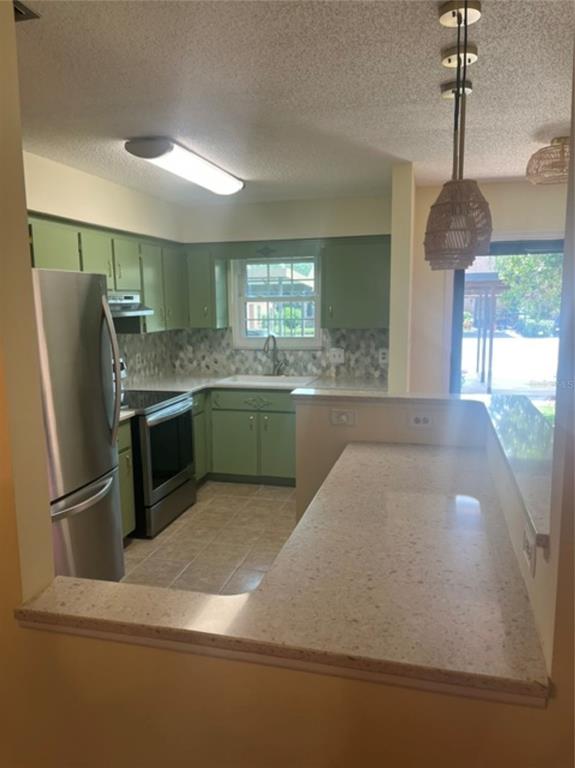 A kitchen with green cabinets, stainless steel appliances, and a breakfast bar with stone countertops — 15 COVE LANE, EUSTIS, FL