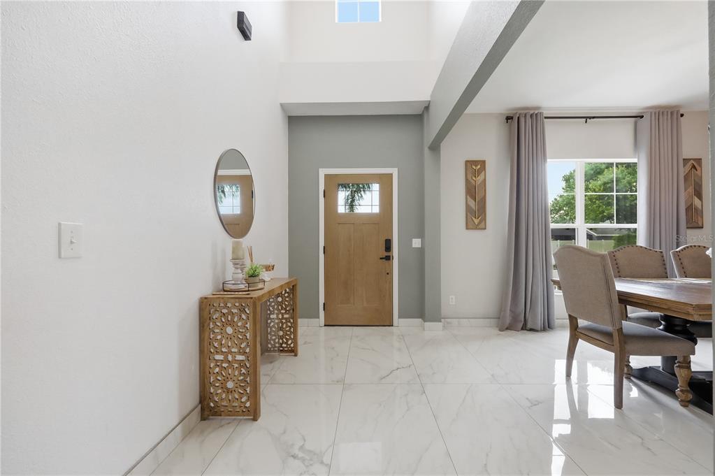 A bright entryway with white marble floors, a wood console table, and a dining area — 3097 BUCKEYE POINTE DRIVE, WINTER HAVEN, FL
