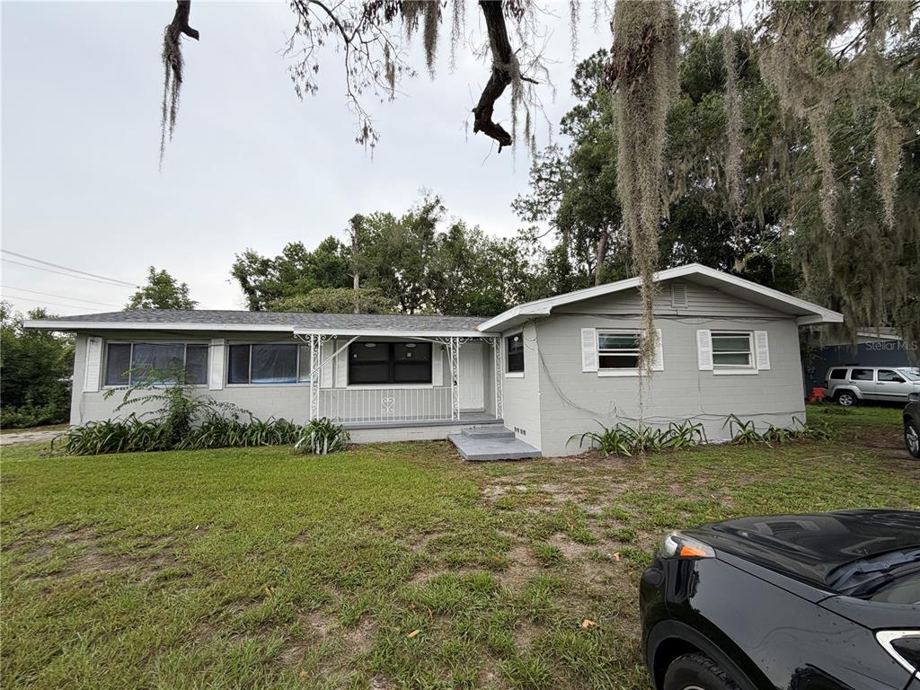 A single-story gray house with a front porch and a lawn under Spanish moss trees — 2715 NE 1ST AVENUE, OCALA, FL