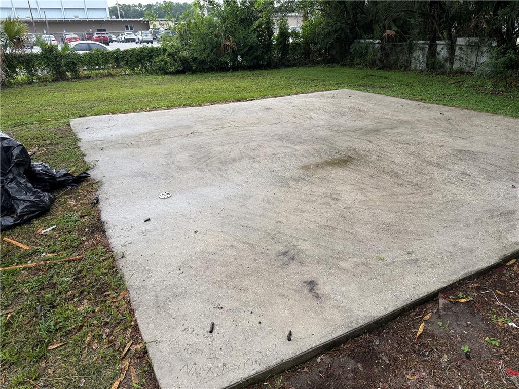 A rectangular concrete slab sits in a grassy backyard near a fence and parking lot — 2715 NE 1ST AVENUE, OCALA, FL