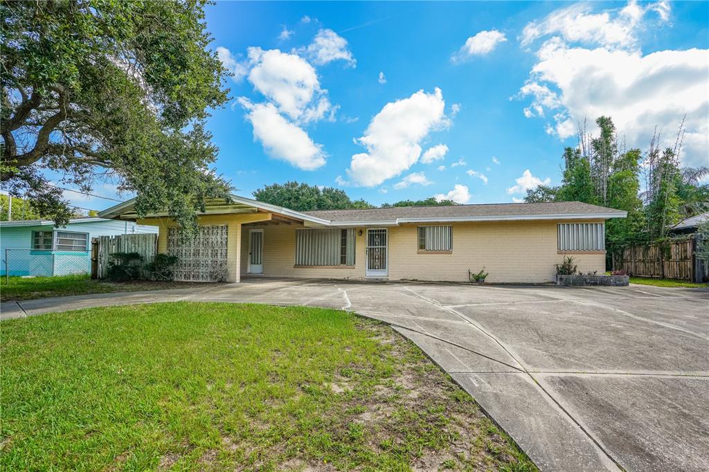 A single-story yellow brick house with a concrete driveway and a covered carport — 2005 SAXON DRIVE, NEW SMYRNA BEACH, FL