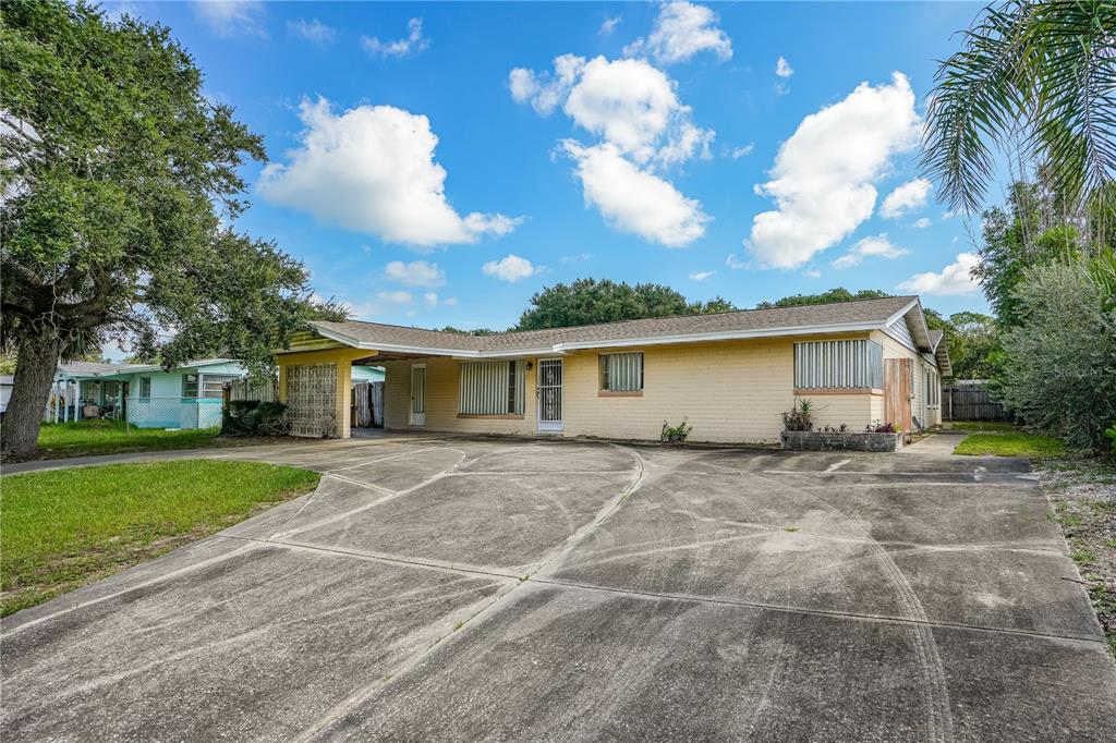 A single-story yellow brick house with a carport and a large concrete driveway — 2005 SAXON DRIVE, NEW SMYRNA BEACH, FL