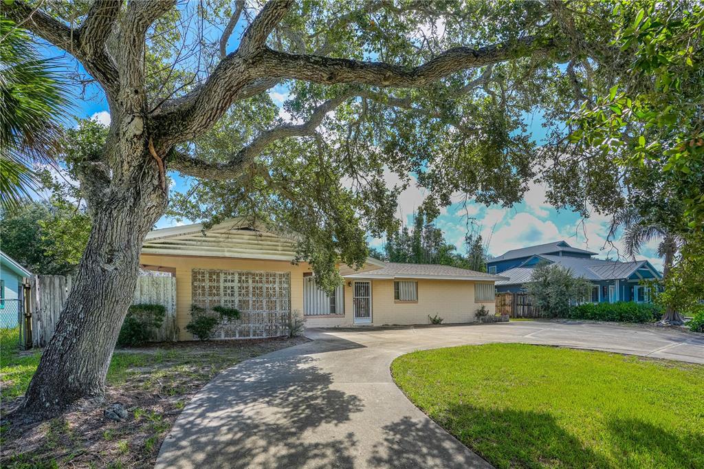 A single-story yellow brick house with a large oak tree and a concrete driveway — 2005 SAXON DRIVE, NEW SMYRNA BEACH, FL