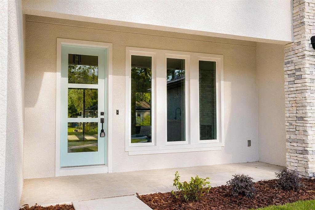 A light blue front door sits beside three tall windows on a covered concrete porch — 14 RENSHAW DRIVE, PALM COAST, FL