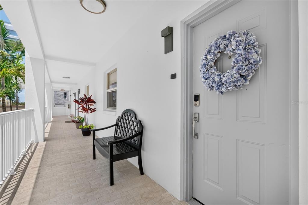 A covered outdoor walkway features a black bench, a potted plant, and a front door — 433 CENTRAL AVENUE, SARASOTA, FL