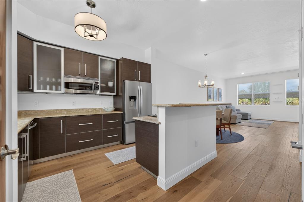 A kitchen with dark wood cabinets, granite countertops, and stainless steel appliances opens to a living area — 433 CENTRAL AVENUE, SARASOTA, FL