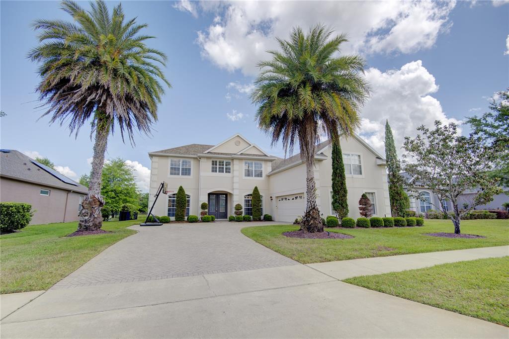 A two-story house with a paved driveway, two palm trees, and a basketball hoop — 1185 STELLAR DRIVE, OVIEDO, FL