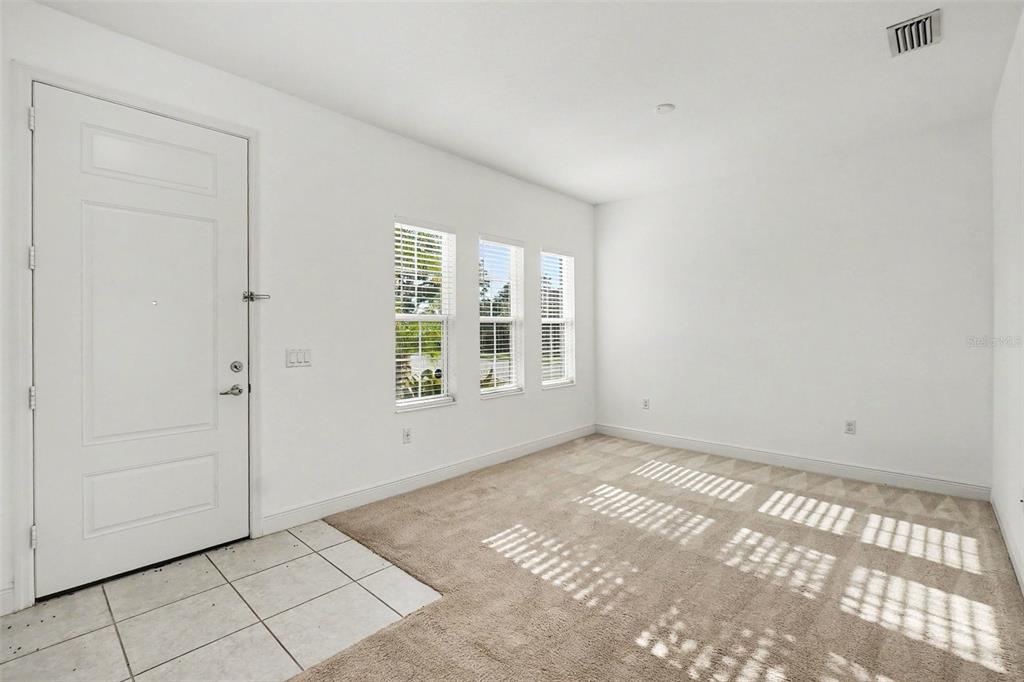 A room with white walls, beige carpet, a tiled entryway, and three windows — 4107 PINE MEADOW DRIVE, PARRISH, FL