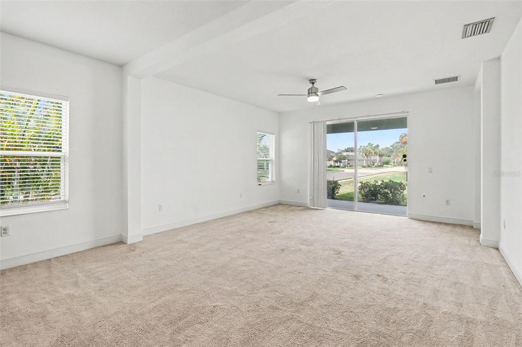 An empty room with beige carpet, white walls, a ceiling fan, and sliding glass doors — 4107 PINE MEADOW DRIVE, PARRISH, FL