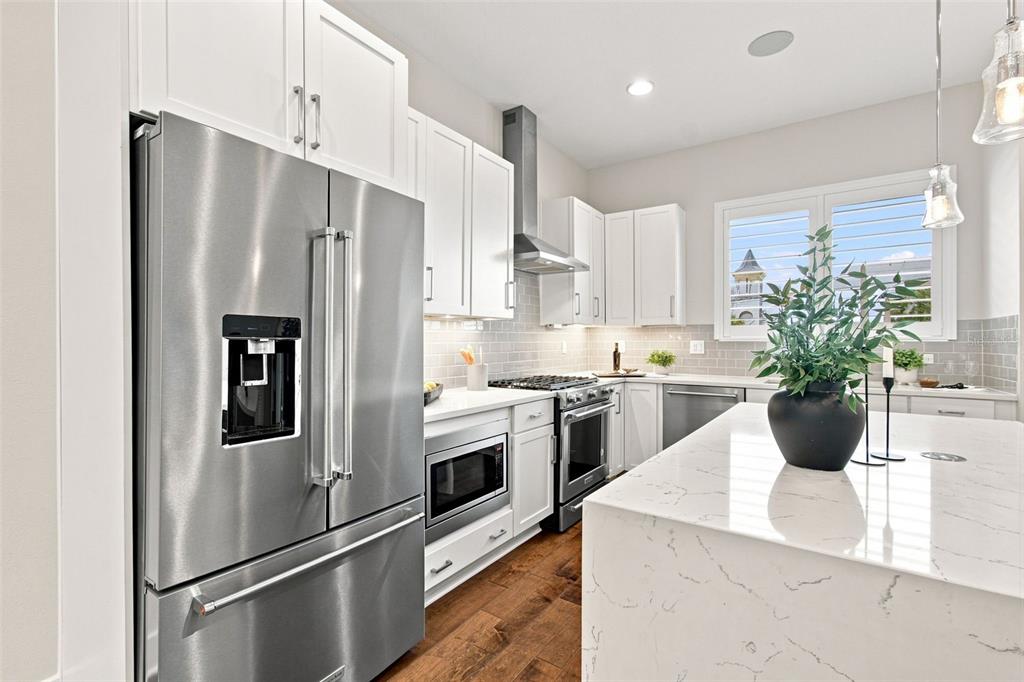 A modern kitchen features white cabinetry, stainless steel appliances, and a marble-topped island — 931 ARLINGTON AVENUE N, ST PETERSBURG, FL