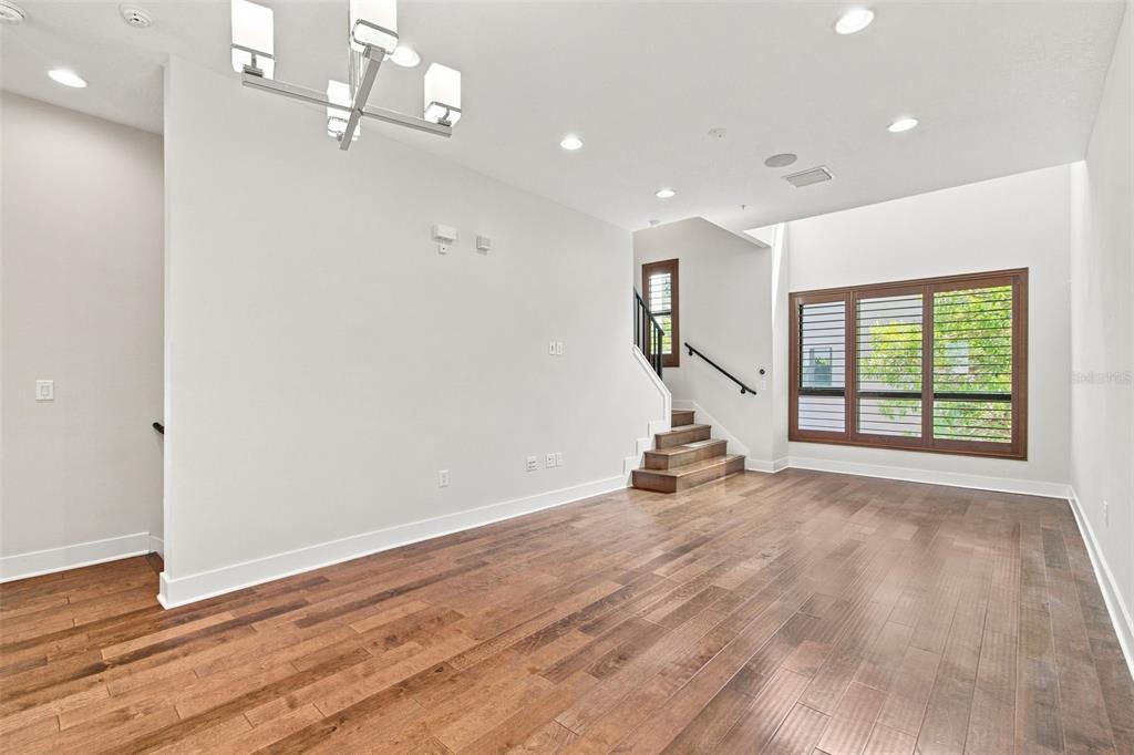 A bright living room features hardwood floors, a modern chandelier, and stairs leading to a landing — 931 ARLINGTON AVENUE N, ST PETERSBURG, FL