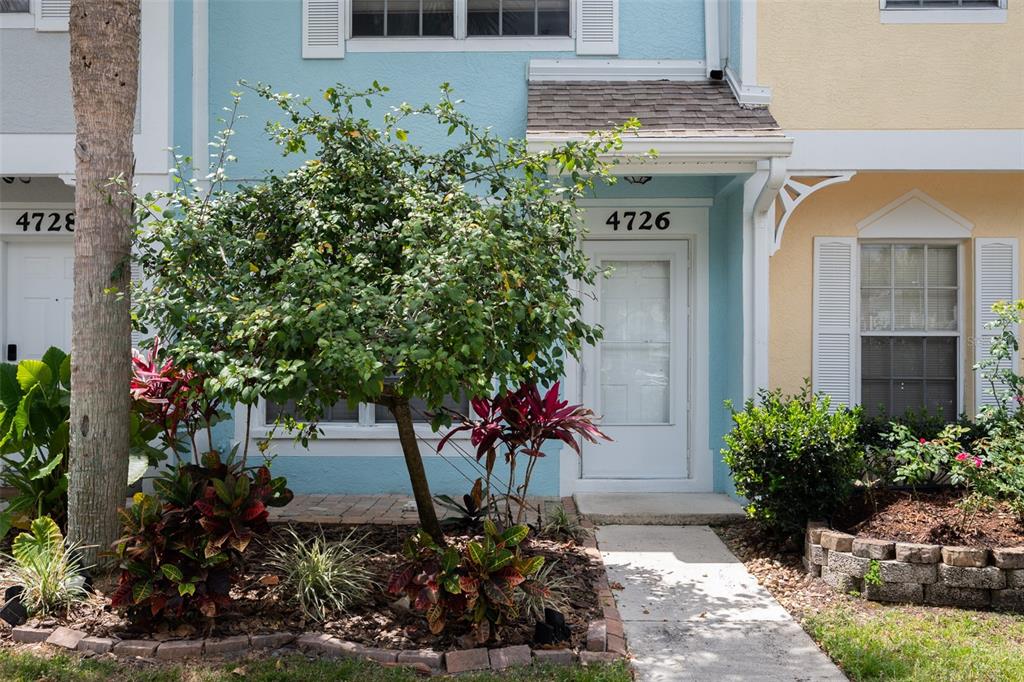The exterior of a light blue townhome features a small tree and landscaped garden beds — 4726 SABAL KEY DRIVE, BRADENTON, FL