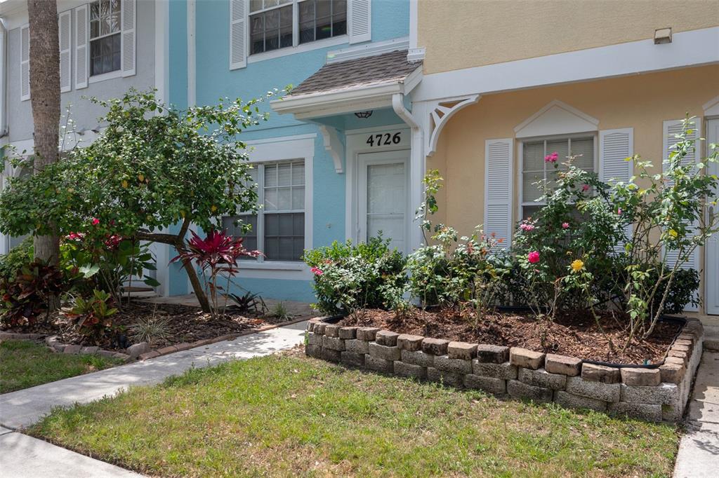 The exterior of a two-story townhouse features a light blue and yellow facade with landscaping — 4726 SABAL KEY DRIVE, BRADENTON, FL