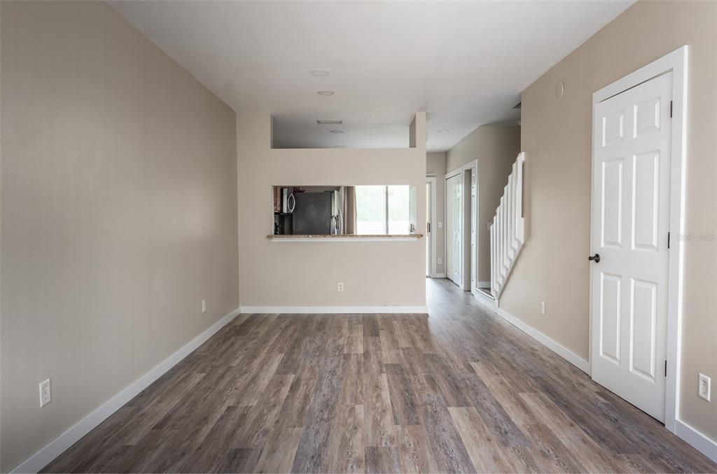 A dining area with wood-look flooring, a kitchen pass-through window, and a staircase — 4726 SABAL KEY DRIVE, BRADENTON, FL