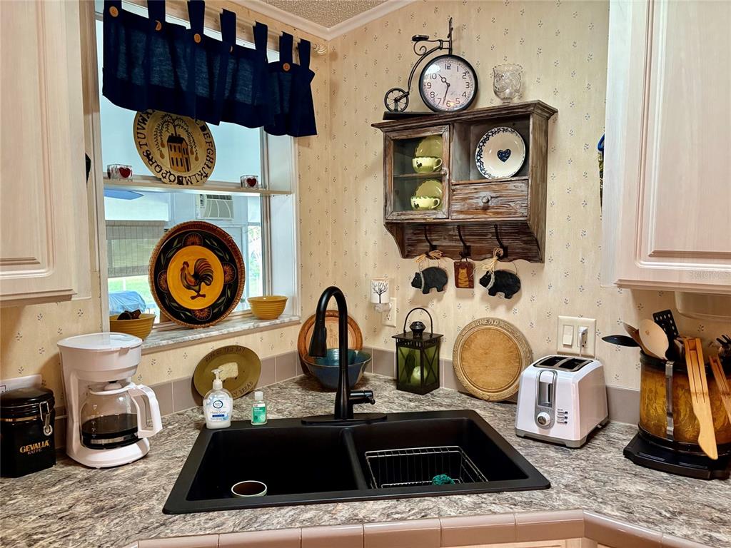 A dining area with a round table sits adjacent to a kitchen with white cabinets — 6600 SCENIC POINT DRIVE SE, WINTER HAVEN, FL