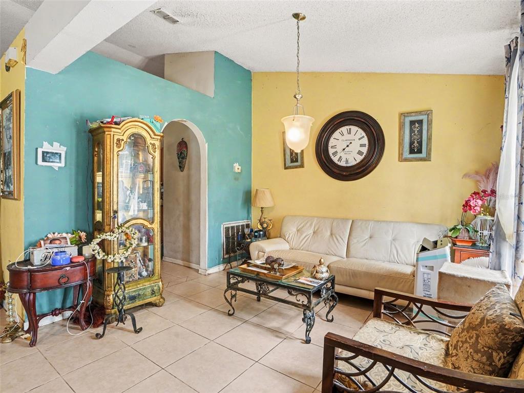 A living room features a white sofa, a glass coffee table, and a large wall clock — 62 HERRING COURT, POINCIANA, FL