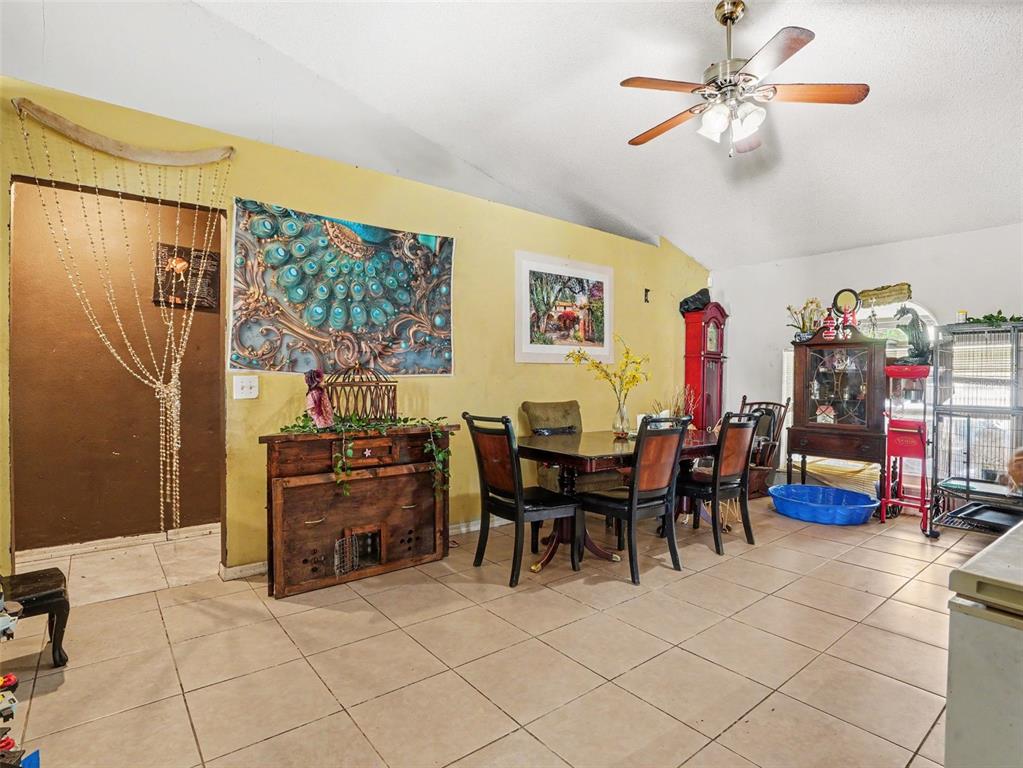 A dining area features tile flooring, a wooden table with chairs, and yellow walls — 62 HERRING COURT, POINCIANA, FL