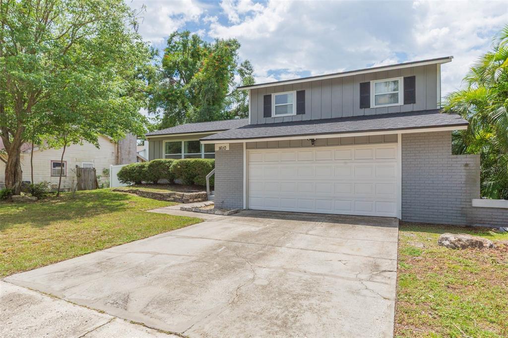 A two-story house with a gray brick and siding exterior, a garage, and a concrete driveway — 1610 BURNING TREE LANE, BRANDON, FL