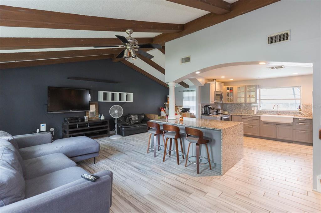 An open-concept living room and kitchen featuring vaulted ceilings with exposed wood beams — 1610 BURNING TREE LANE, BRANDON, FL