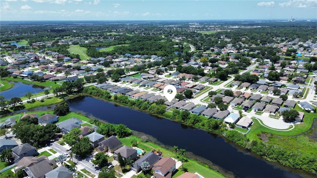 An aerial view shows a suburban neighborhood with houses surrounding a long, narrow lake — 12922 FIELDMOOR COURT, RIVERVIEW, FL