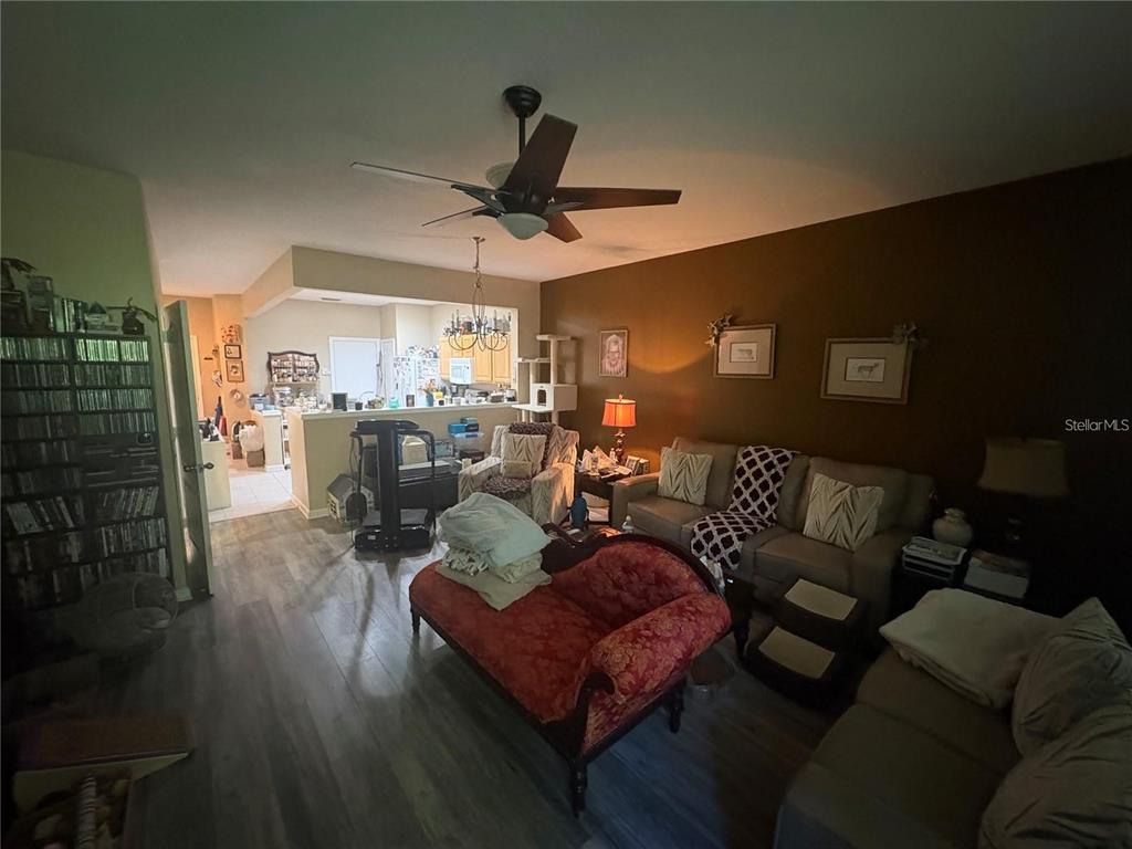 A living room features wood-look flooring, a ceiling fan, and a red upholstered chaise lounge — 4605 BARNSTEAD DRIVE, RIVERVIEW, FL