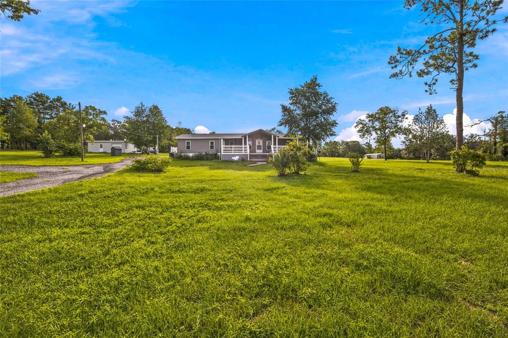 A single-story manufactured home sits on a large, grassy lot with scattered trees — 5351 NE 121ST TERRACE, WILLISTON, FL