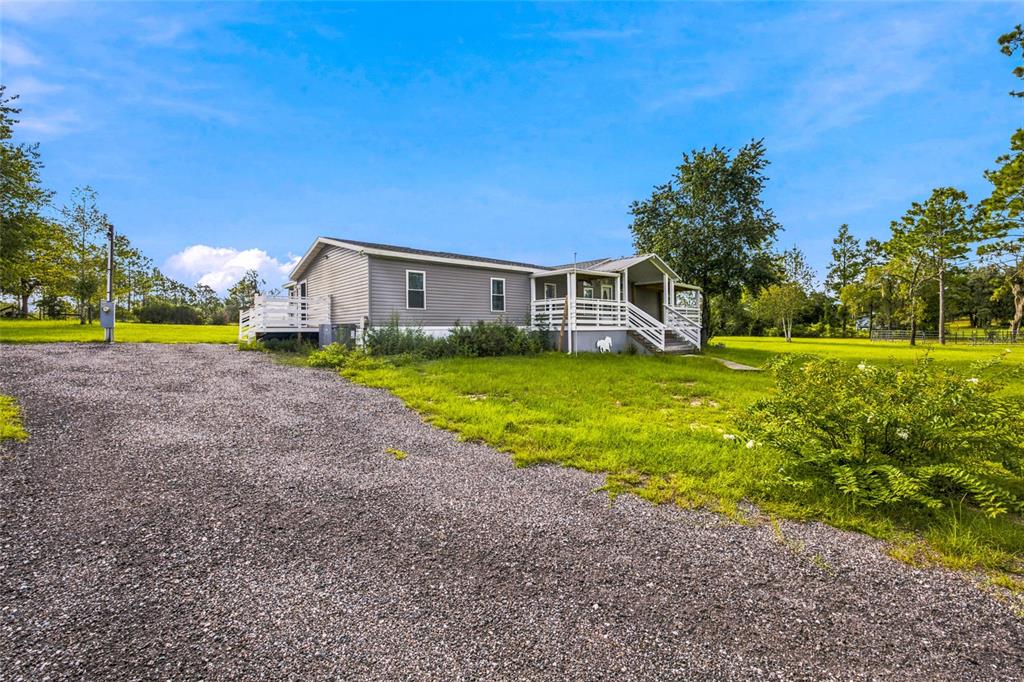 A single-story manufactured home with a gravel driveway and a covered front porch — 5351 NE 121ST TERRACE, WILLISTON, FL