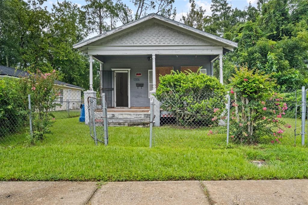 A small, gray, single-story house with a front porch sits behind a chain-link fence — 2117 TUSKEGEE ROAD, JACKSONVILLE, FL